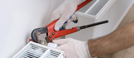 Topenář při montáži radiátoru v bytě