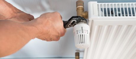 Topenář při montáži radiátoru v bytě